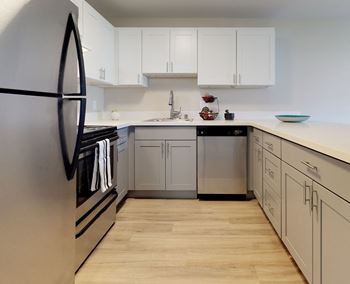 U-shaped kitchen with stainless steel appliances, white countertops and cabinets and hardwood flooring. 